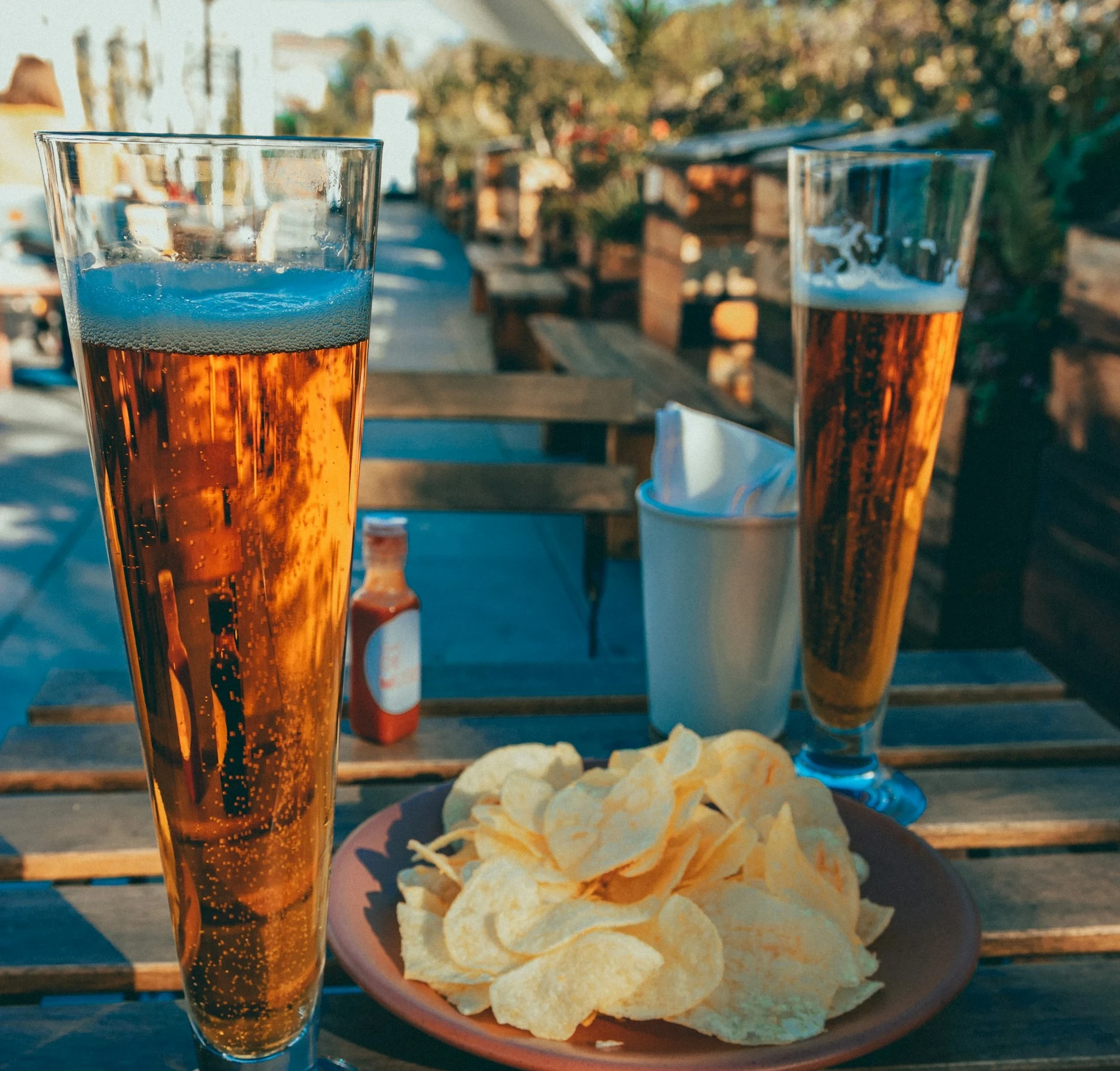Deux verres de Pilsner posés sur une table avec une assiete de chips